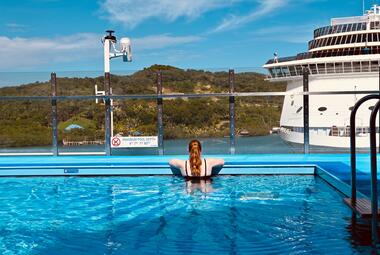 young woman looks out at the distance while in a pool on Carnival Celebration